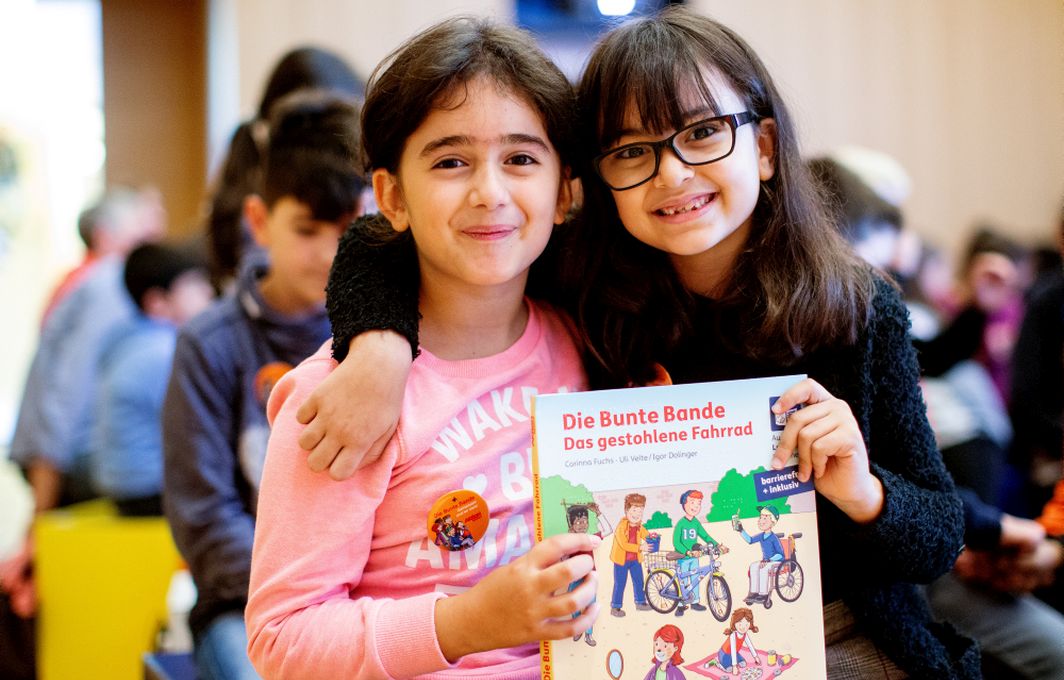 Zwei Kinder halten ein Buch der "Bunten Bande" in die Kamera.