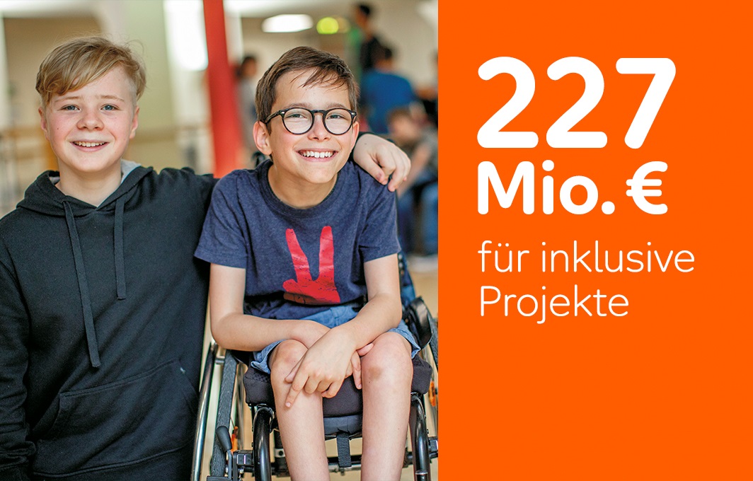 227 Millionen Euro gingen 2021 an soziale Projekte für Inklusion. Auf dem Bild sieht man zwei Freunde. Der eine sitzt im Rollstuhl.