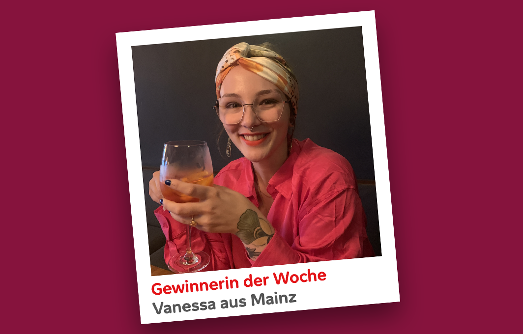 Die Gewinnerin Vanessa hält ein Glas Wein in der Hand und schaut glücklich in die Kamera.