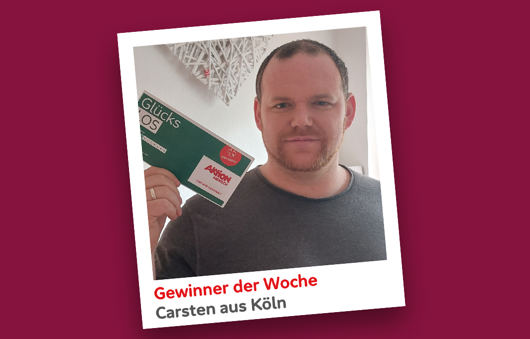 Der Gewinner Carsten hält sein Los in die Kamera.