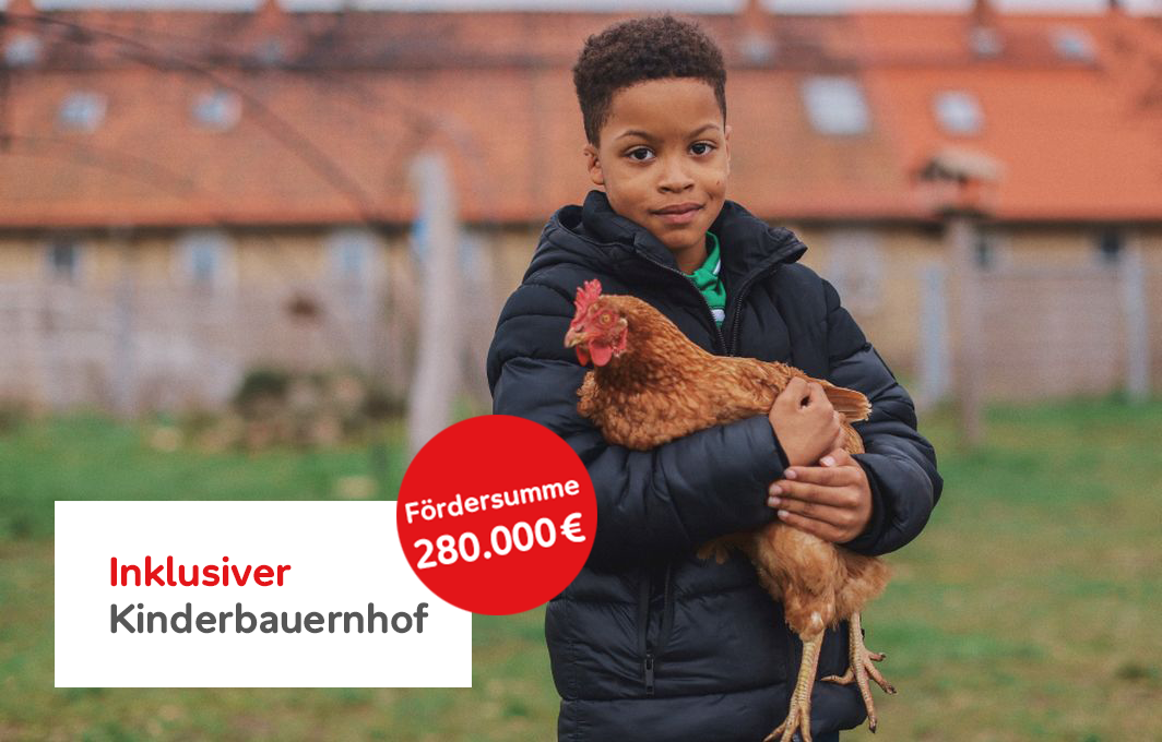 Ein Junge hält ein Huhn im Arm. Textbox: Inklusiver Kinderbauernhof