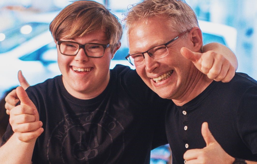 Gewinner Tobias und ein Mitarbeiter des CafÃ©s stehen Arm in Arm nebeneinander und recken lachend ihre Daumen in die Höhe