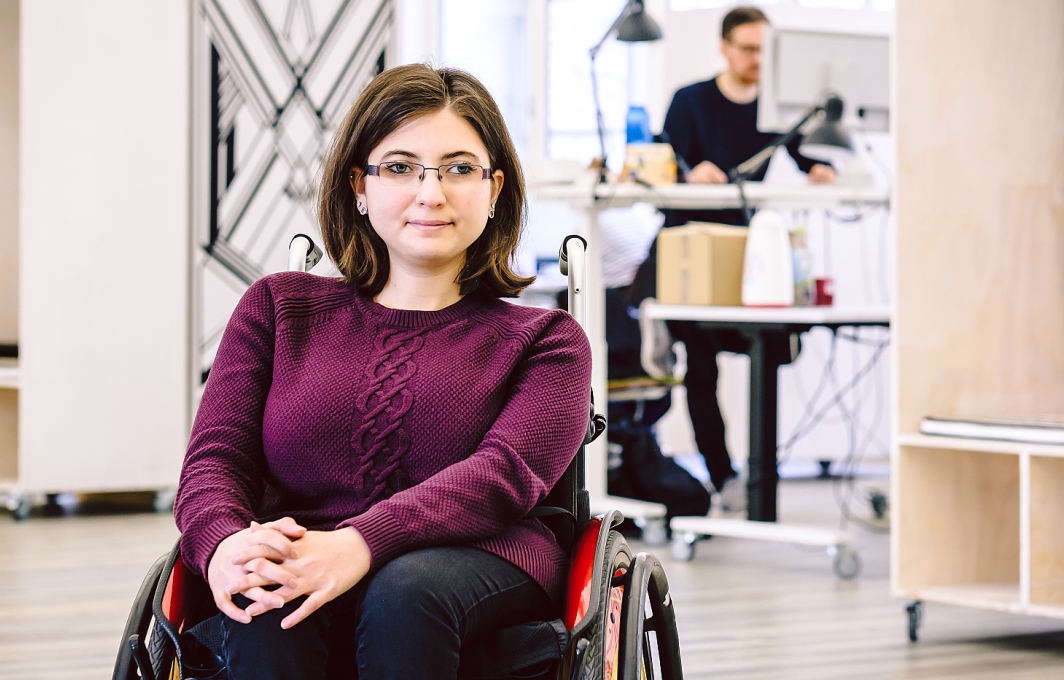 Eine Frau im Rollstuhl in einer Arbeitsumgebung im Büro.