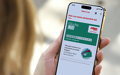 Auf einem Mobiltelefon ist die App der Aktion Mensch geöffnet. Darin ist das grüne Glücks-Los der Aktion Mensch zu sehen.